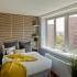 Arabella 101, interior, bedroom, large window, yellow blanket, accent wall, wood floor