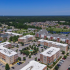 aerial view of exterior apartment buildings with fountain and parking lot on sunny day