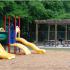 Hunters Run playground area with wood chip padding under play area and bbq area with grills, picnic tables and pergola.