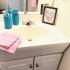 Bathroom: White cabinet & marbled sink with crystal faucet, mirror, Soft pink hand towels, Blue soap dispenser, Nice photo frame for additional home touch.
