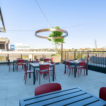 Rooftop outdoor dining tables with stylized lighting and seating at Modera Broadway apartments in Seattle.