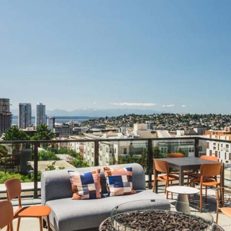Lounge seating, firepit and dining table overlook Seattle and look towards the mountains at Modera Broadway apartments.