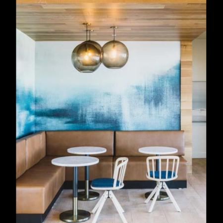 Banquet-seating nook with small tables and stylish lighting and artwork at Modera Broadway apartments.