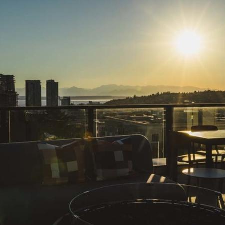 Rooftop deck lounge area with the sunset behind it over the mountains and the city at Modera Broadway apartments.