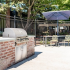 Outdoor brick BBQ next to the sparkling pool with covered seating area