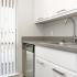 Contemporary kitchen sink with gooseneck faucet, white cabinets, vertical blinds over window, and stainless dishwasher.