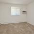 Large bedroom with beige carpeting and wall air conditioning unit