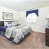 Bedroom with beige carpet, a blue bedspread and blue curtains at Carlisle Park apartments for rent