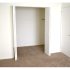 Carpeted model bedroom with large open closest at Oak Tree Apartments in Newark, DE.