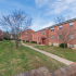 Grassy courtyard with sidewalks outside of brick residential buildings at Evergreen Club apartments for rent