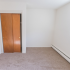 Moderate sized bedroom with two closets and baseboard heating at Evergreen Club apartments for rent