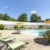 Swimming pool with green lounge chairs and tables/chairs with yellow umbrellas surrounding. White privacy fence encircles pool area. at Summit Place apartments in Methuen, MA.