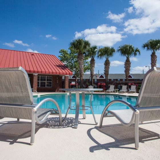 Campus Crossings on Alafaya, exterior, sparkling blue swimming pool, lounge chairs, building, palm trees