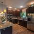 kitchen with vinyl plank flooring, granite countertops, stainless appliances, dark brown wood cabinets, a dishwasher, and a mounted microwave