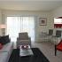 Living room with grey couch, large sliding door, and red accent chair at The Commons at Fallsington apartments for rent in Morrisville, PA