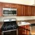 Kitchen with brown cabinetry and stainless steel appliances at The Commons at Fallsington apartments for rent