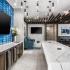 Club room bar area with large granite table, mounted tv with blue tile backsplash