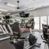 Community fitness center with various exercise equipment and ceiling mounted televisions.