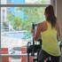 Young woman working out on step machine, looking out window to the pool.