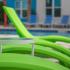 Close up of green lounge chairs with the pool in background.
