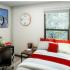 Block75 Apartments, interior, bedroom, window, red and white bed, desk, chair, night stand, clock on wall