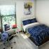 Block75 Apartments, interior, bedroom, blue and white bed, desk, chair, gray wood floor, window