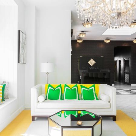 1810 The Social, interior, spacious seating area, chandelier, decor is white with green and yellow accents, large sofas, large window, reception area, black wall, black sign, black desk