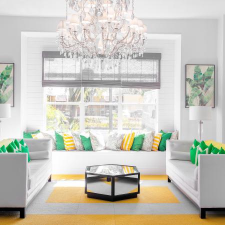 1810 The Social, interior, spacious seating area, chandelier, decor is white with green and yellow accents, three large sofas, large window