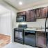Caton House Apts; Interior, kitchen, expresso cabinets, over the cabinet storage, marble countertops, black appliances, gas range, over range microwave with vent and light, dishwasher, fridge, GFI outlets, garbage disposal