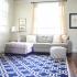 A brightly lit living room with light gray furniture and a deep blue rug. | Rental Houses near Los Angeles AFB