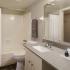 River View Apartments, interior, bathroom, gray tones, wood floor, white cabinet, large mirror, sink, toilet, shower/tub, white curtain