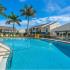 Belleza, exterior, sparkling blue swimming pool, clubhouse, apartments with balconies, lounge seating, palm trees