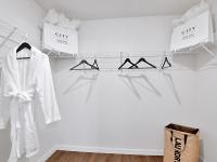 Walk in closet at our homes in Apopka, FL, featuring white clothing racks, clothes hangers, and robes.
