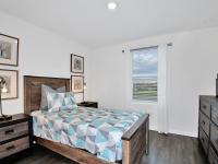 Model bedroom in one of our homes in Apopka, FL, featuring wood grain floor paneling and wooden furniture.