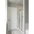 Stand up shower lined with chrome, light grey flooring, white door and light grey painting