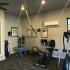 Other view of the gym, with a few work out machines, yoga ball, and an AC box on the wall next to a window