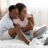 couple  sitting in front of laptop on bed.