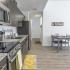 University Pointe, interior, kitchen, wood floor, dark cabinets, stainless steel appliances, stove/oven, dishwasher, refrigerator, lemon floor mat, dining table for two, hallway