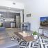 University Pointe, interior, living room, gray leather sofa, black and white area rug, tv, coffee table, kitchen, wood floor, dark cabinets, stainless steel appliances, stove/oven, dishwasher, refrigerator,