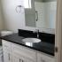 Bathroom vanity with generous black quartz counterspace, white cabinetry, a large mirror mounted above the sink.