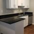 Kitchen sink with gooseneck faucet, stainless steel dishwasher, white cabinetry and generous counterspace.