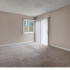 Spacious bedroom with beige walls, new carpet, and a sliding glass door that opens up to the oversized balcony