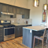 Crescendo Apartments, interior, kitchen, wood floor, dark cabinets, stainless steel appliances, refrigerator, oven/stove, microwave, dishwasher, breakfast bar counter and chairs, gray front door,