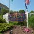 Blue and red Governor Mifflin Apartments property sign surrounded by flowers and flags