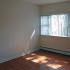 Large window letting in abundant natural light to apartment living area with hardwood flooring