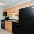 Kitchen with brown cabinets and black appliances at Concord Court apartments for rent in Aston, PA