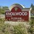 Knollwood Apartments property sign surrounded by ferns on a sunny day