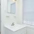 White bathroom with overhead lighting and sink with vanity