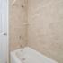 Brown tiled bathroom shower with white tub in Phoenixville, PA apartment for rent