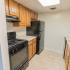 Model kitchen with tiled floors and modern black appliances at Park Court Apartments in Reading, PA.